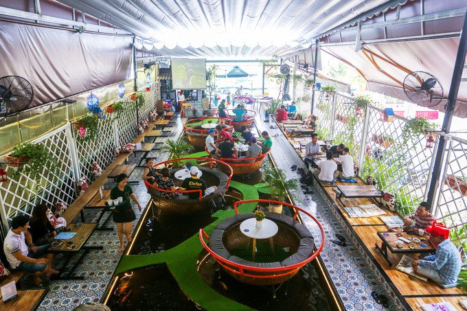 Bàn khách ngồi trên thuyền thúng đặt trên hồ cá Koi tại Koilands Coffee